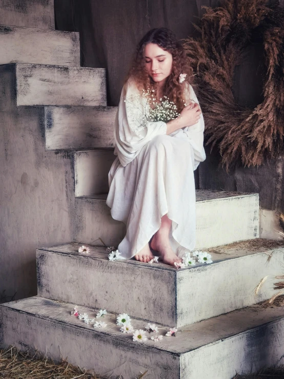 woman sitting on stairs in white outfit next to wreath