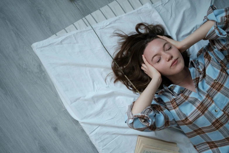 the woman is laying down in her bed and reading the book