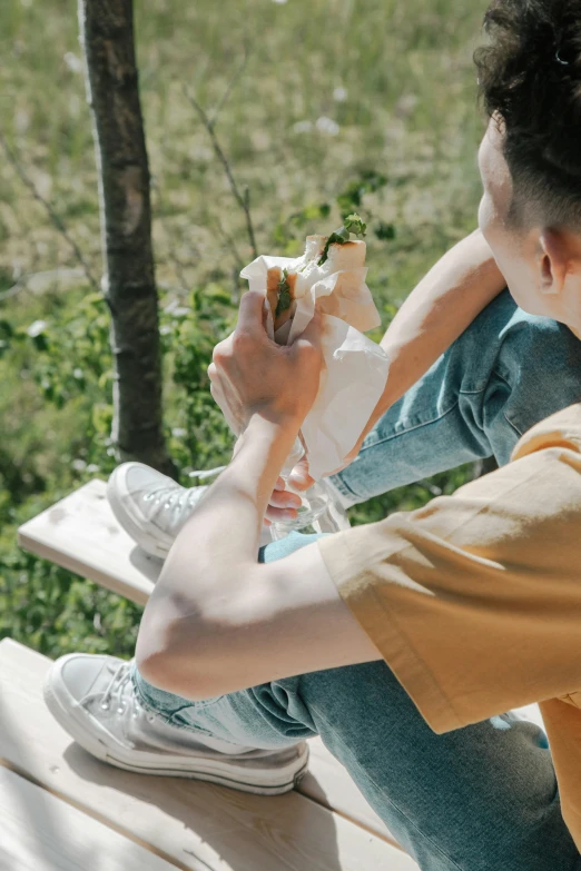 two boys sit and eat a sandwich on a bench