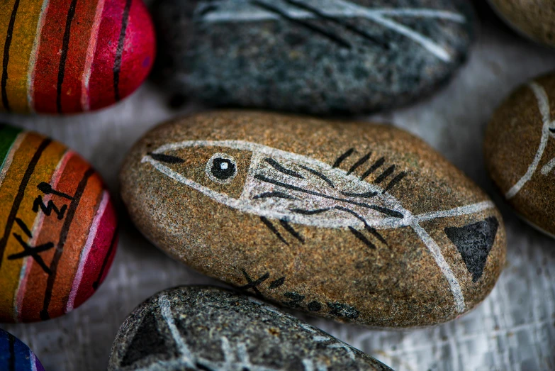 small rocks painted with an image of an fish