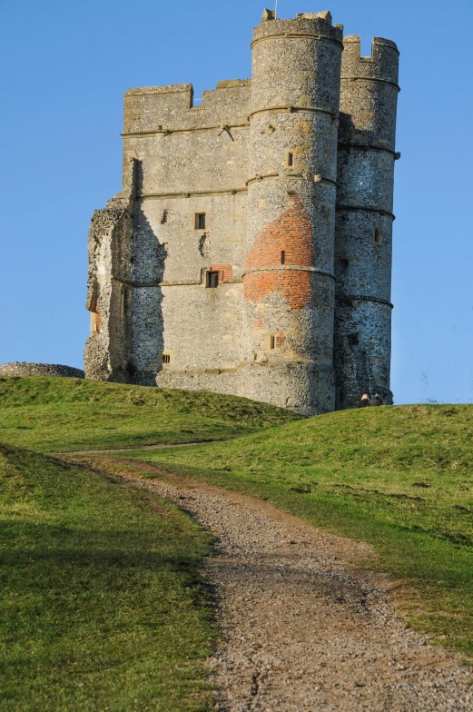 a dirt road going past a castle on a hill