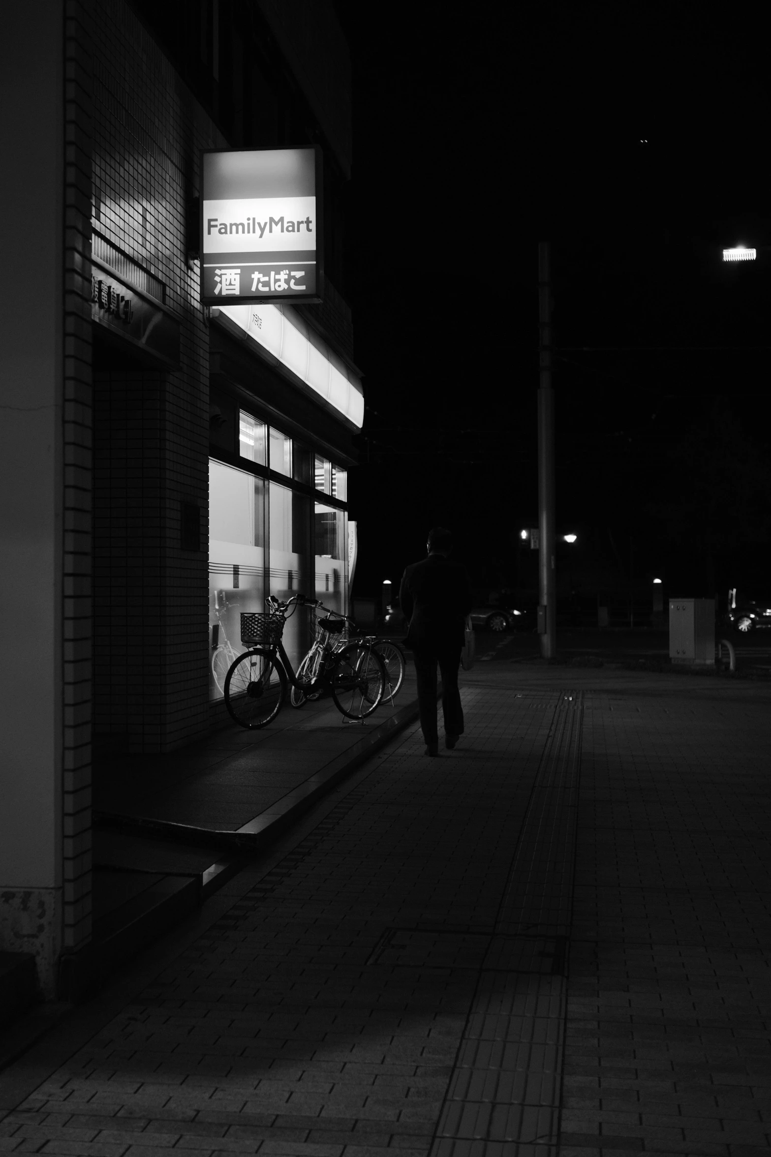 a person walking down a sidewalk at night