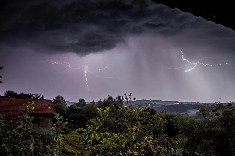 a cloud that has storm coming in the background and there are two lightning strikes