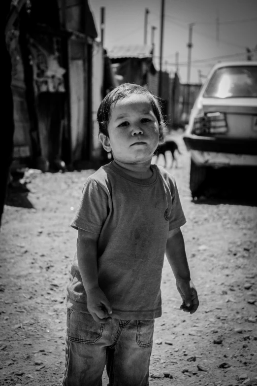 a child standing in the street with a car behind it