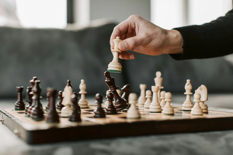 a person moving a white piece on a chess board