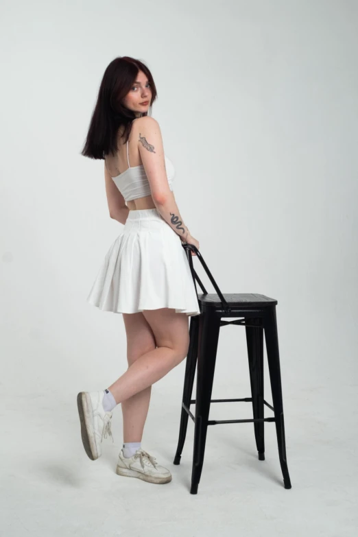 a woman in white skirt standing next to chair