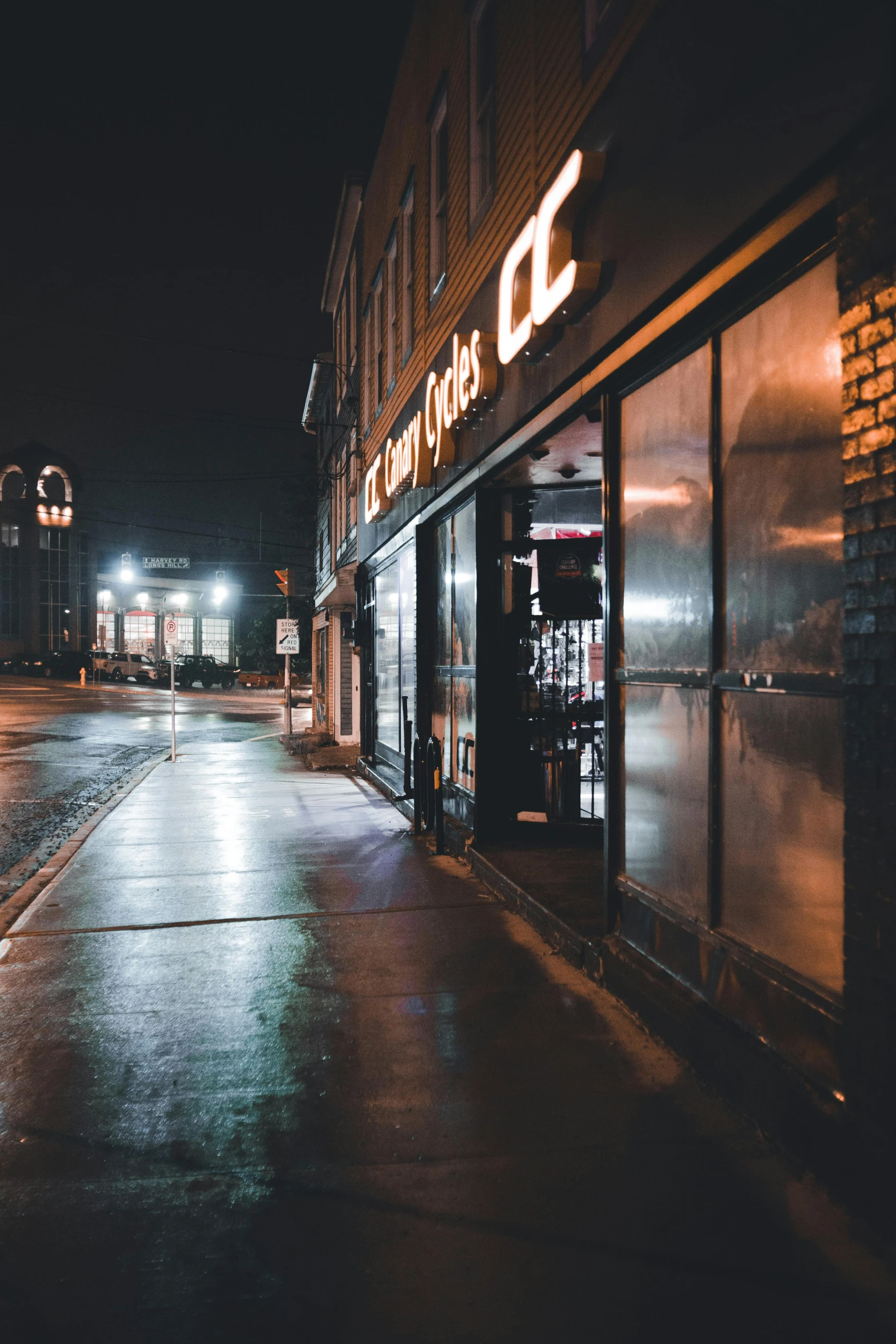 a dark city street with no traffic is lit by the lights