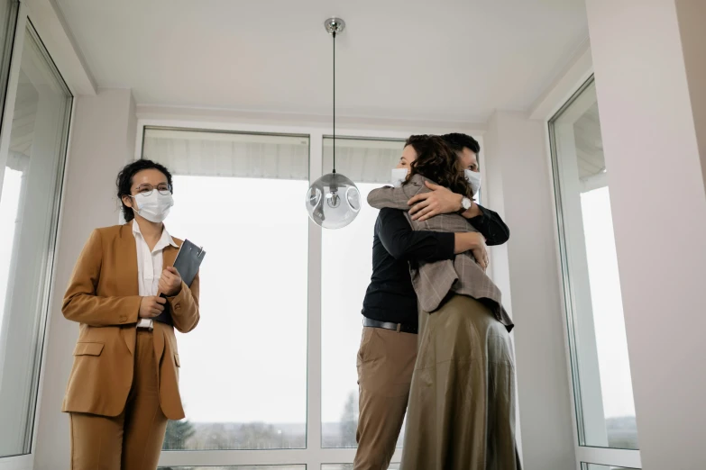 a couple of women standing by a window with masks on