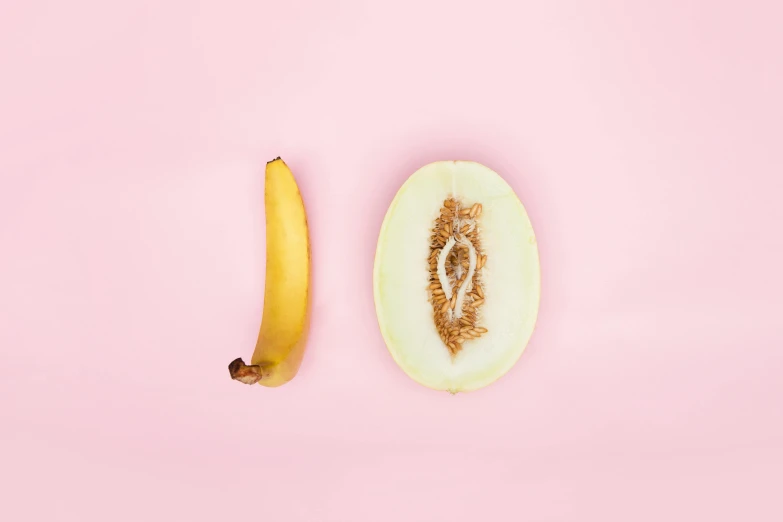 a banana and half an apple on pink background