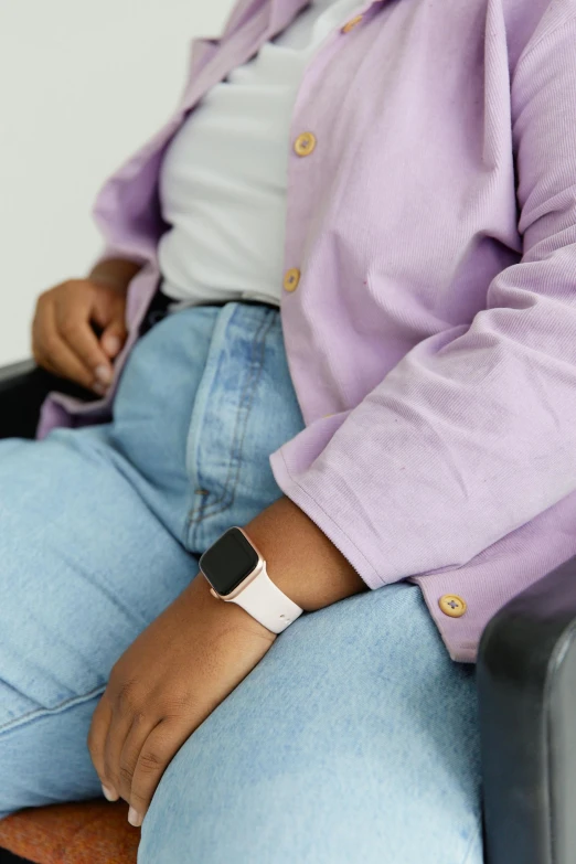 a woman in blue jeans and a white watch sits