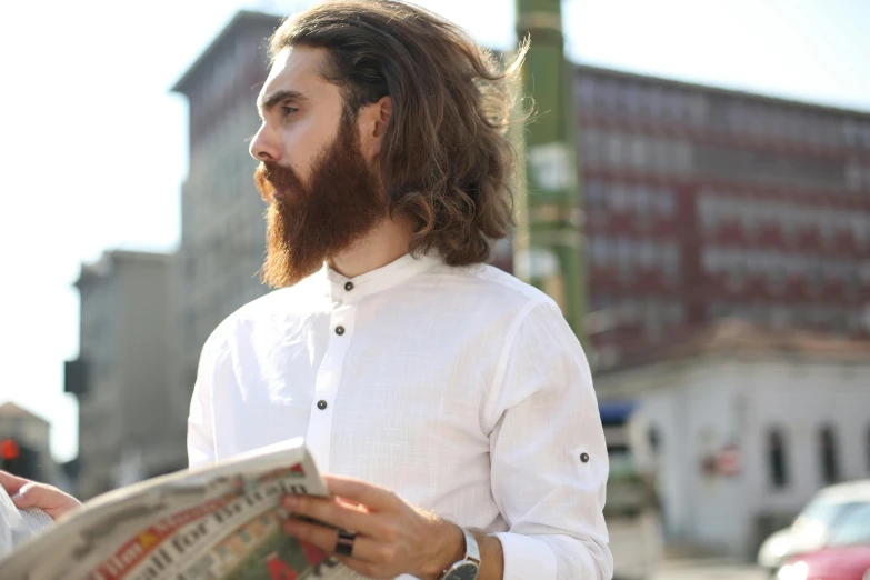 the man with long hair is holding a newspaper