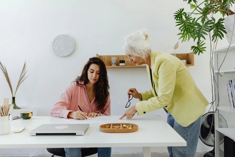 a woman standing over a white table with a laptop