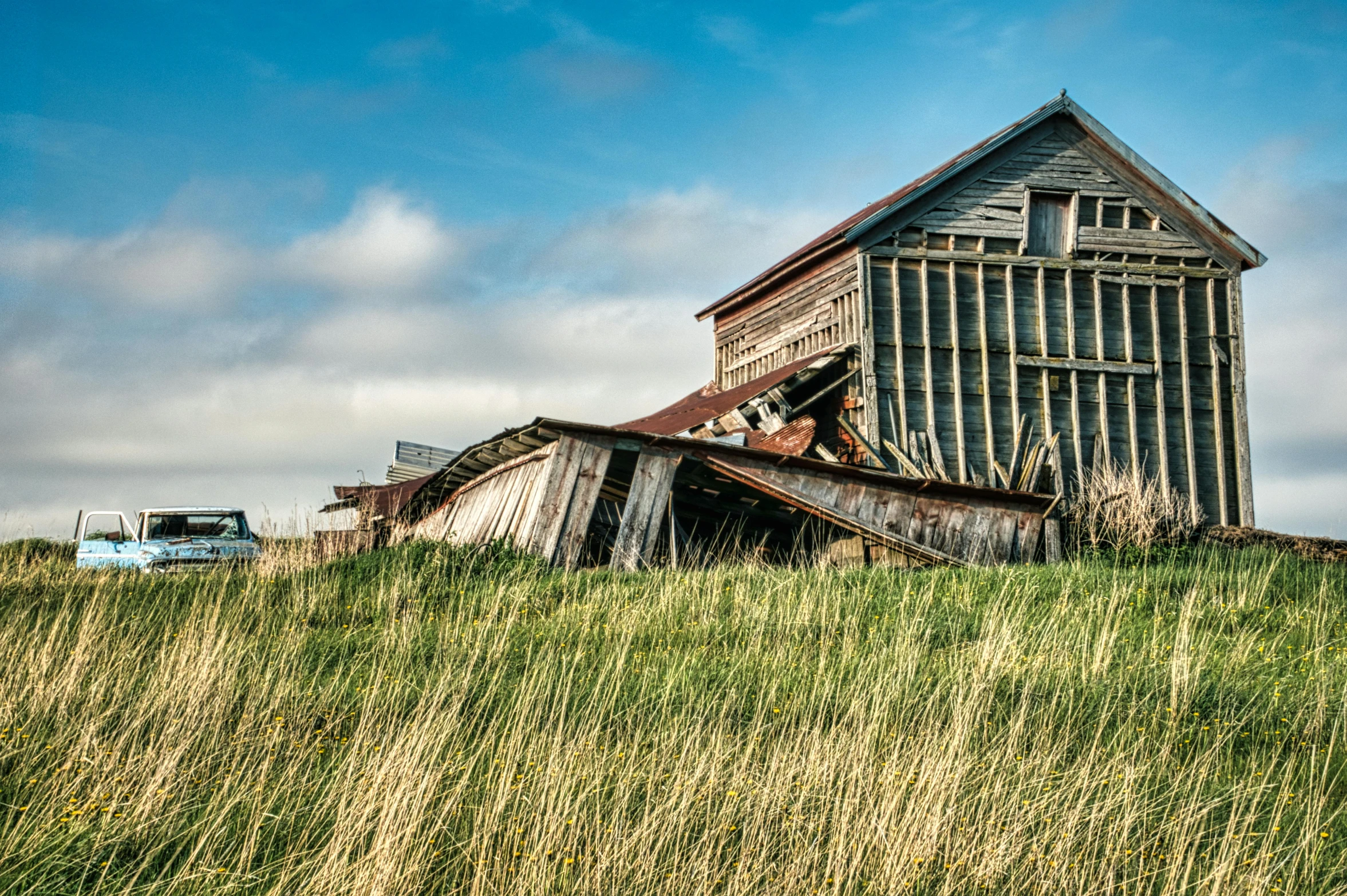 an old house that is falling apart and standing in the grass