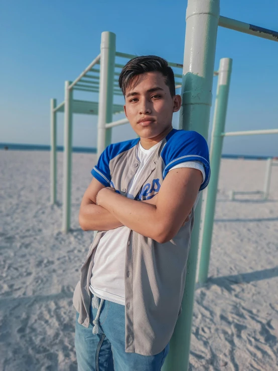 a man standing on top of a sandy beach next to a tall pole