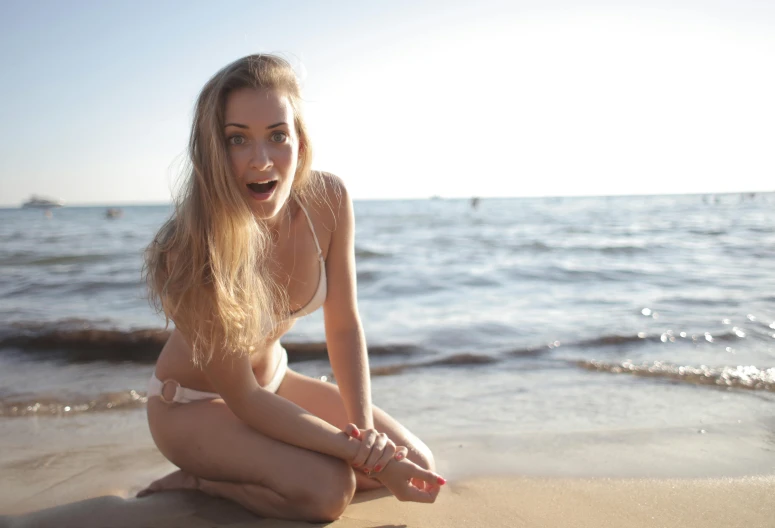 a  woman sitting on the beach with her mouth open