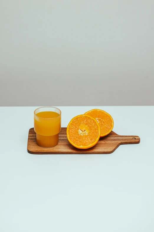 a small wooden tray with sliced oranges and a glass of orange juice