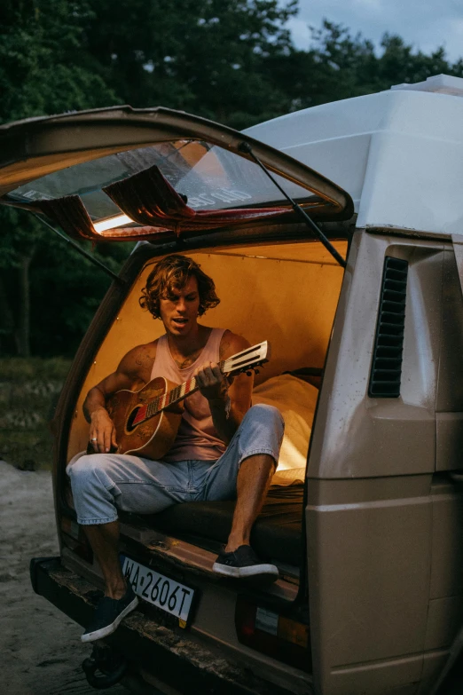a young man playing music in the back of a van