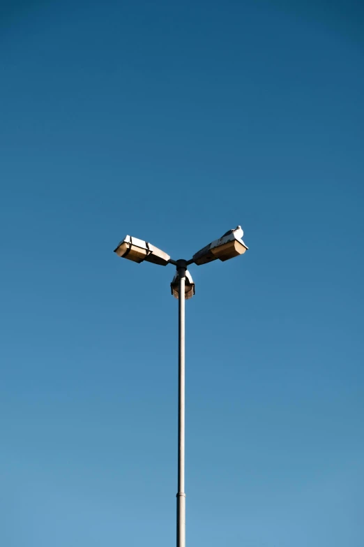 a lamp post with two lamps on top against a blue sky