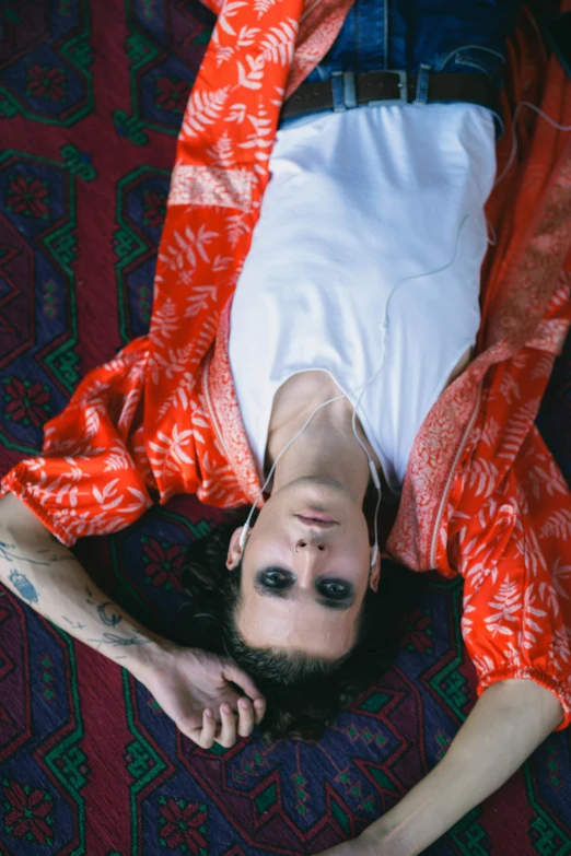 a young man laying on his stomach wearing an orange floral outfit