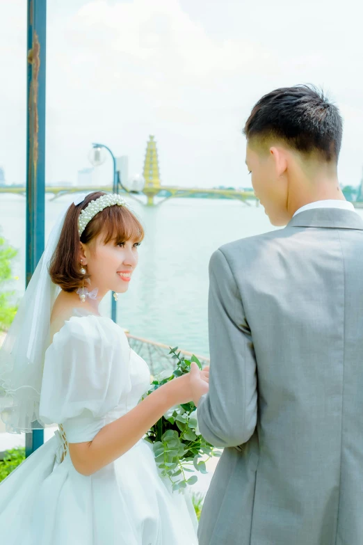 a man and a woman in wedding outfits standing by a lake