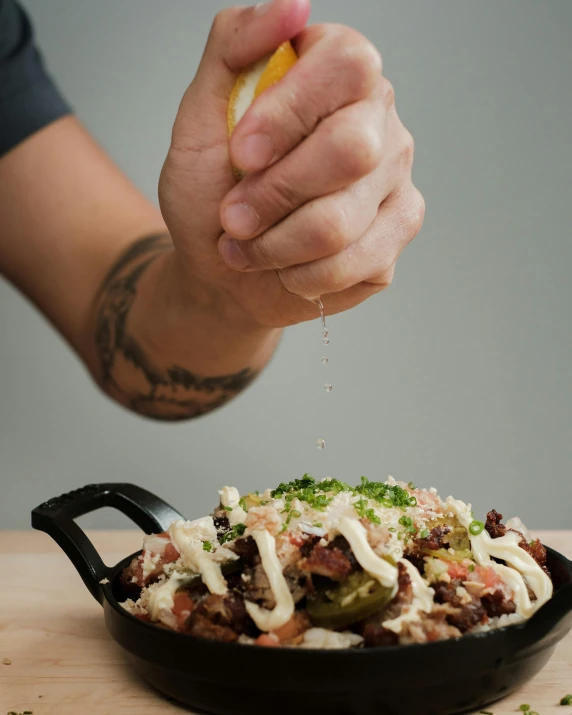 a hand sprinkling topping over the top of a large bowl of food