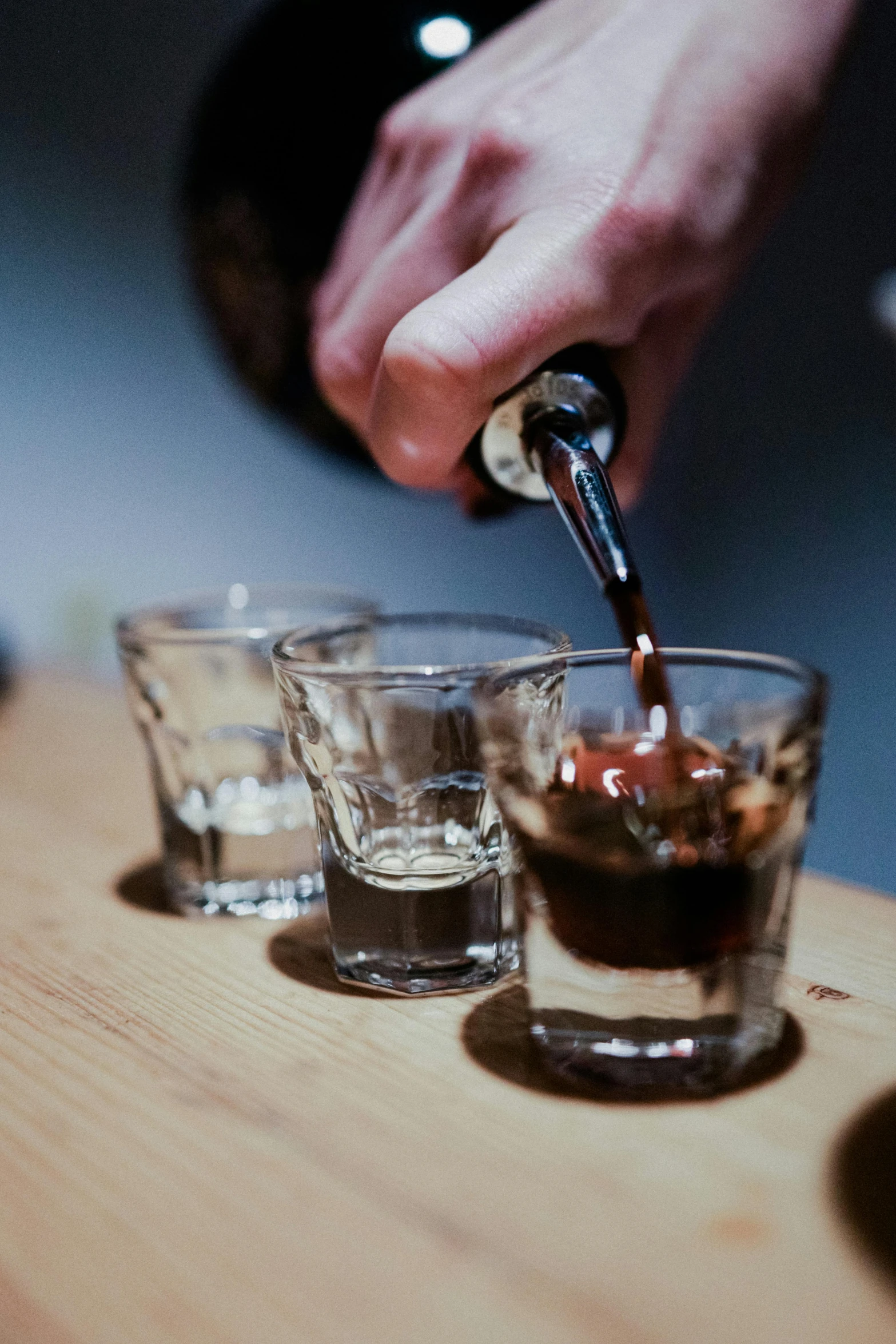 an image of man pouring a beverage into four glasses