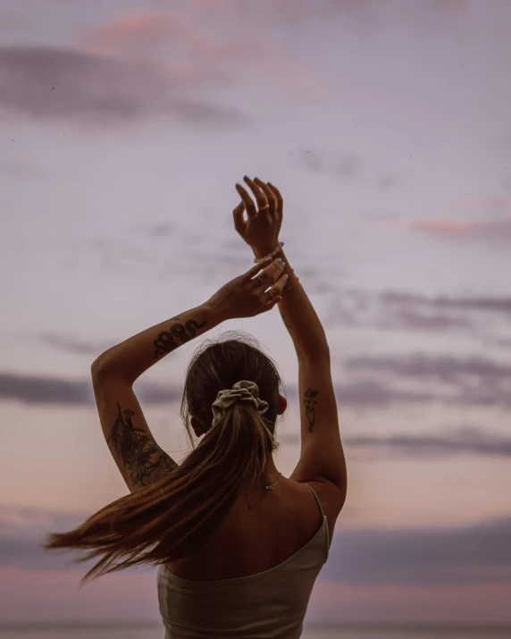 the woman is practicing yoga outdoors with her arms raised