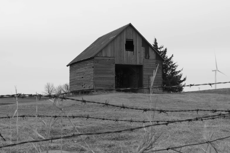 black and white po of a barn by a barbed wire fence