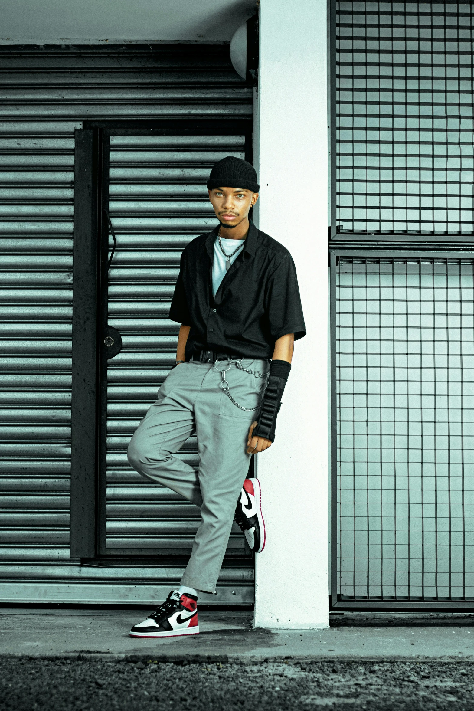 a man wearing a black shirt and a pair of gray sweat pants with black lace up socks stands in front of a garage door