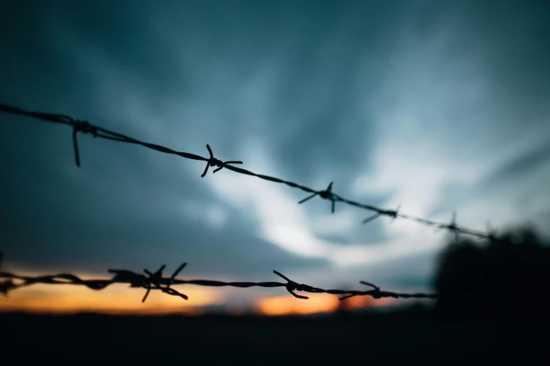 barbwire fence with sunset in the background