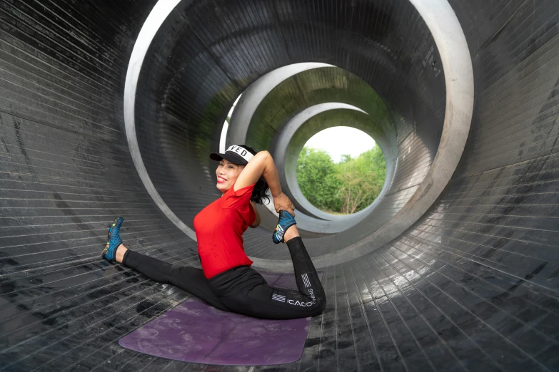 a woman on a yoga mat in front of a large tube