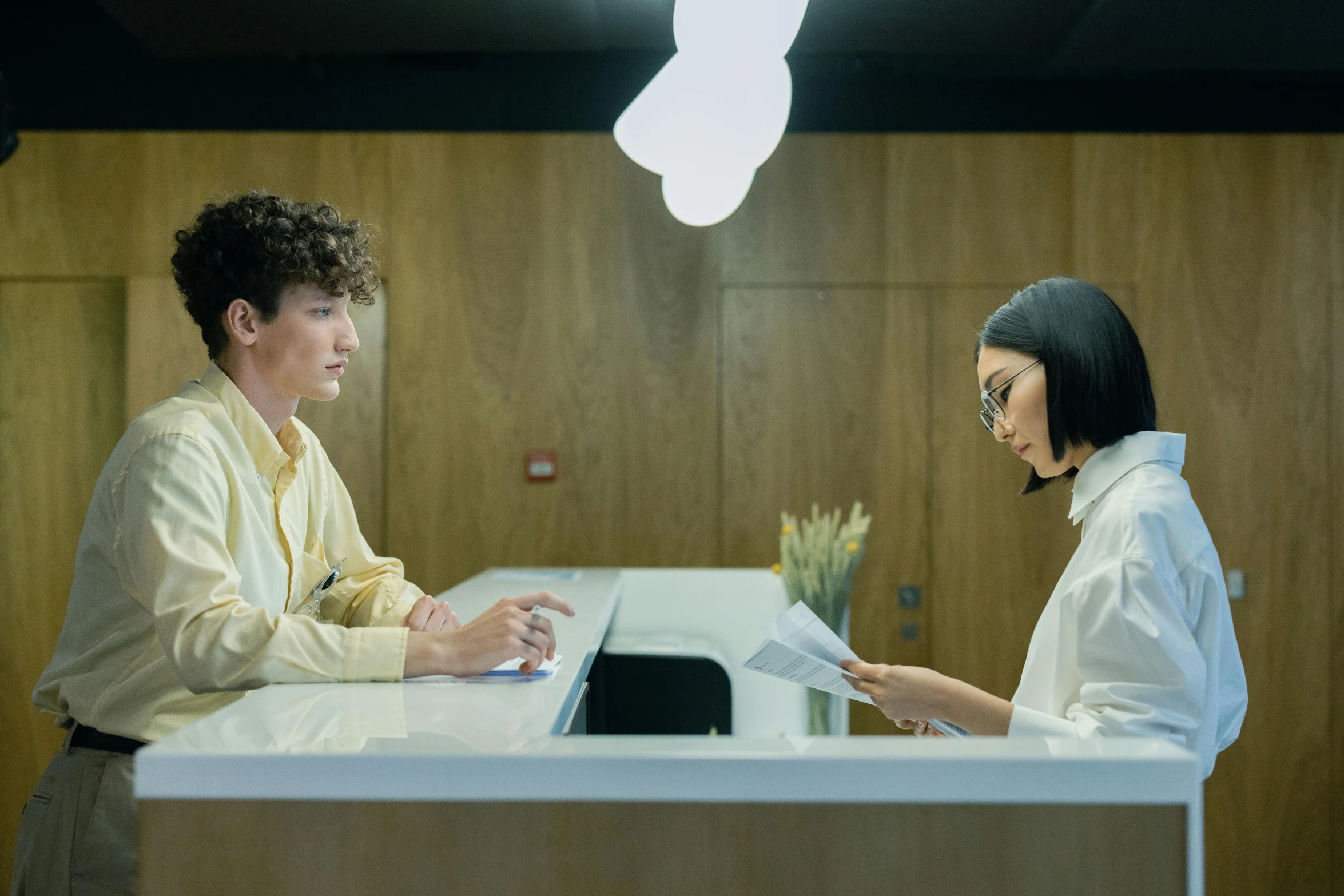 a young lady is sitting at a desk interviewing a young person