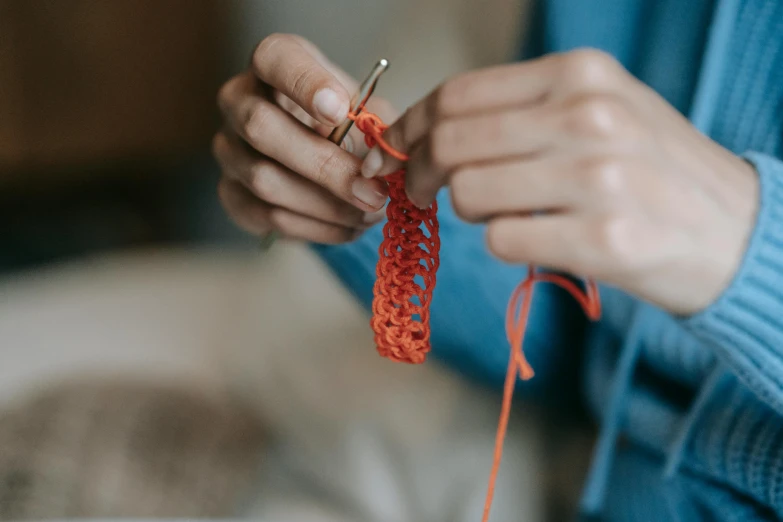 a woman is holding onto a red string with a sewing pin