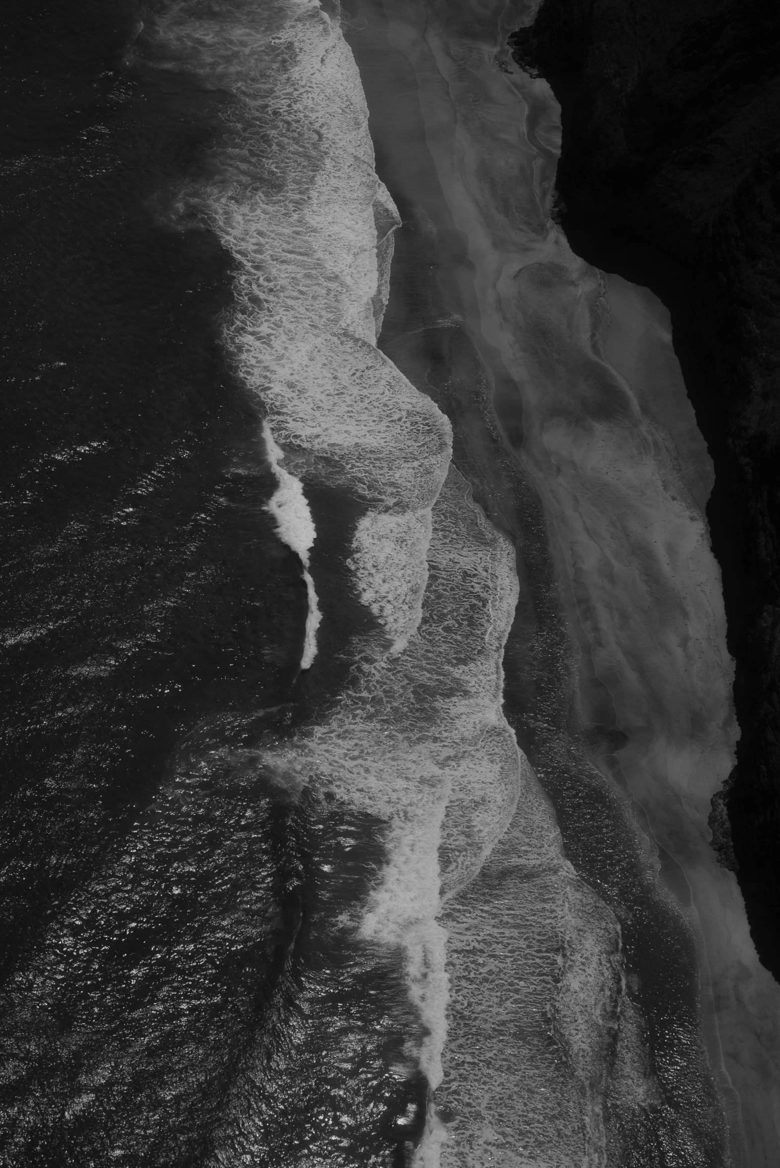 a long and skinny white beach with a wave coming in