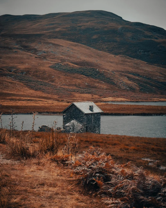 a lonely house sits beside a large body of water in the countryside