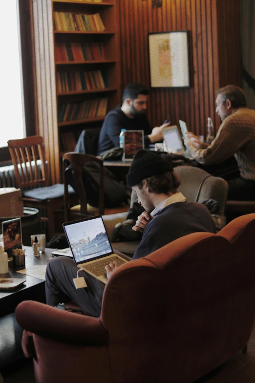 several men sitting at a table in the liry with laptops and books