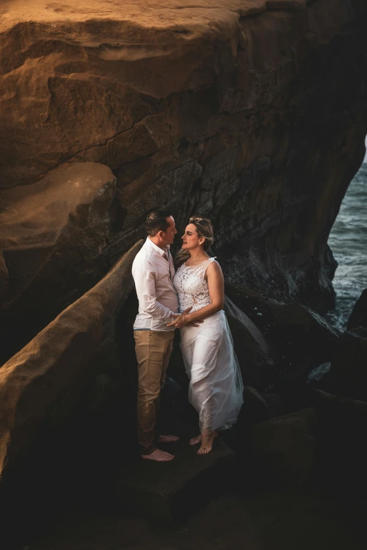 a man and a woman emcing each other near a cliff