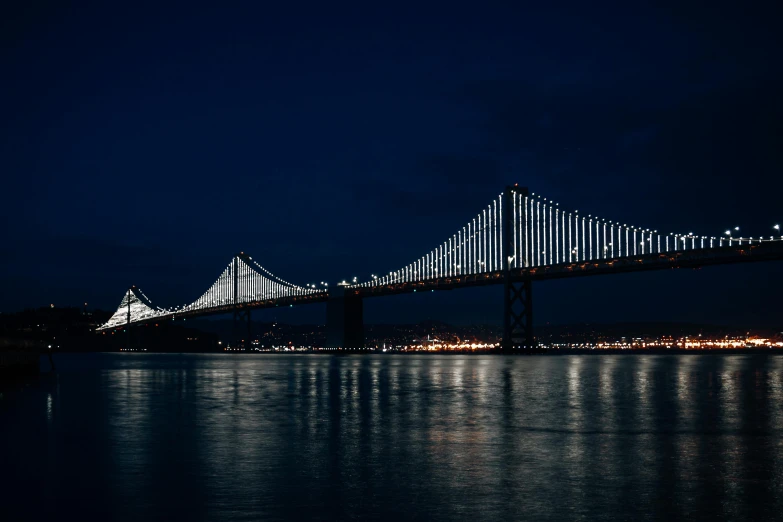 a very tall bridge sitting above the ocean in a dark sky