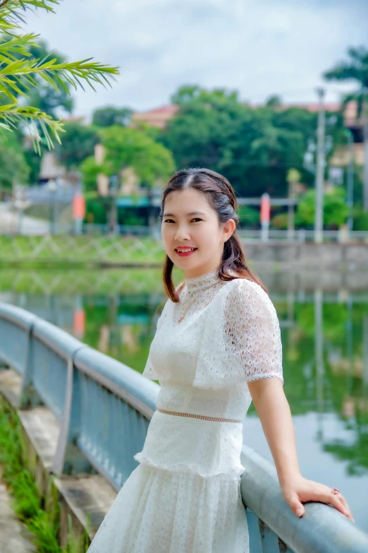 a woman poses for the camera while leaning against a metal railing