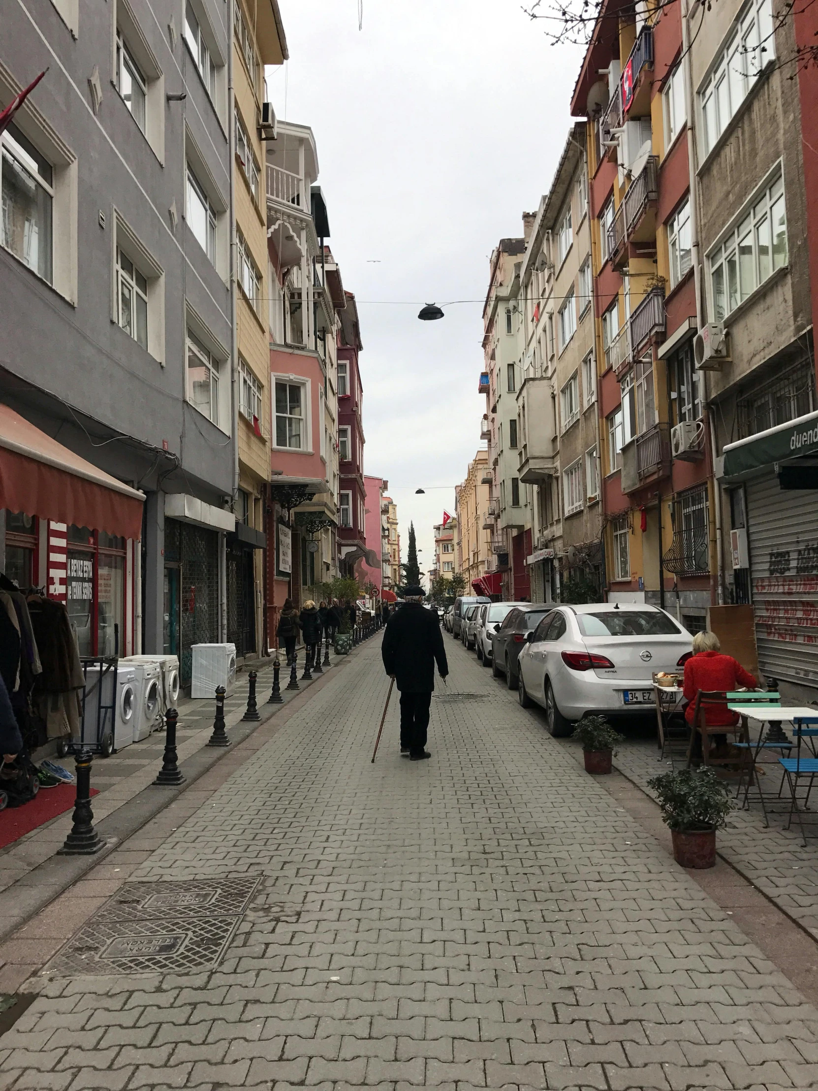 a street lined with several cars and people walking on it