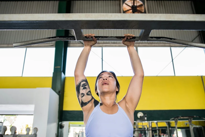 a woman is holding onto a large bar in the gym