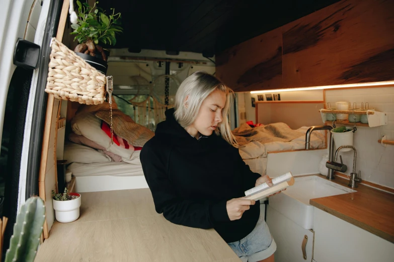 a woman with grey hair stands in front of a small bedroom