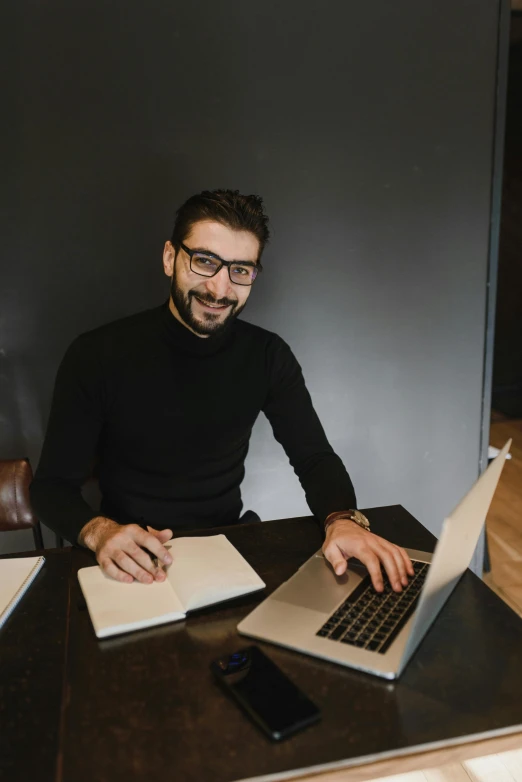 a man sitting at a table with his laptop and notebook