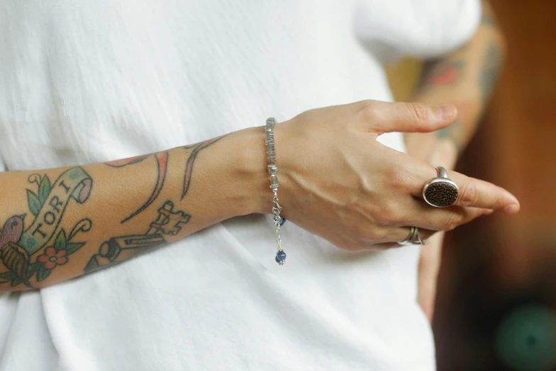tattooed arm with small chain around it in a white shirt