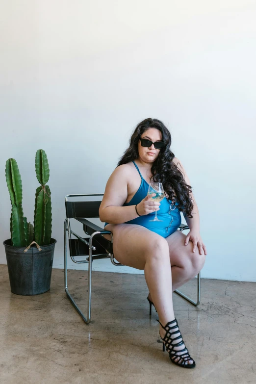 a woman sitting on a chair next to a cactus