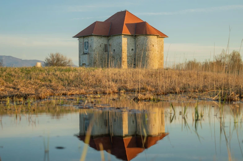 the old grain tower and water tank reflect in the still pond