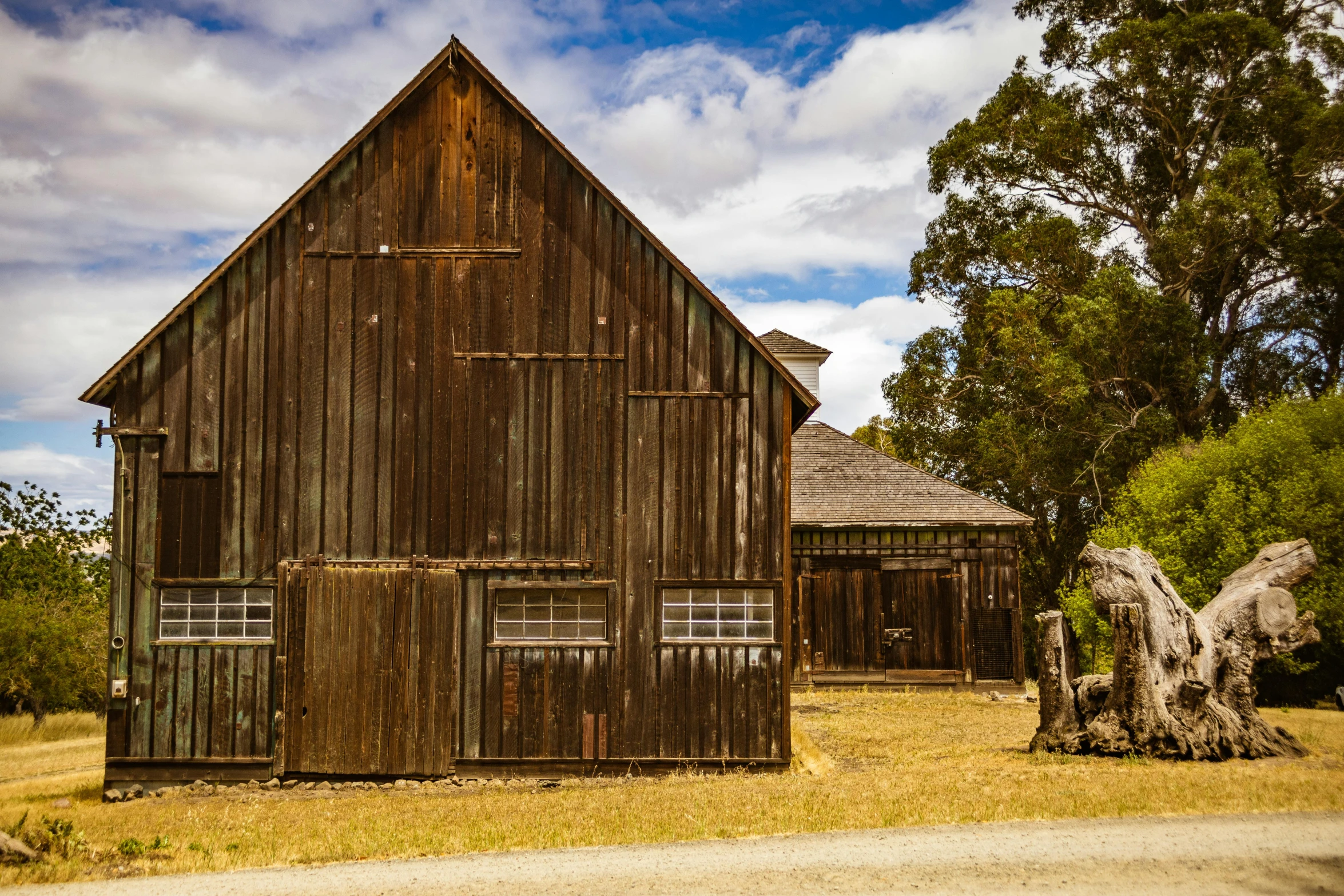 an old barn sits in the middle of a large field