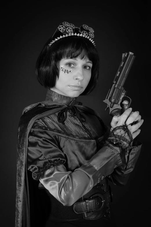 a girl dressed up in a black costume and hat holds up a toy gun