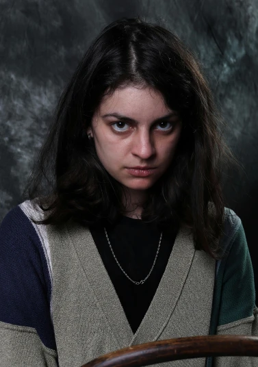 a woman is wearing a sweater and looking at the camera