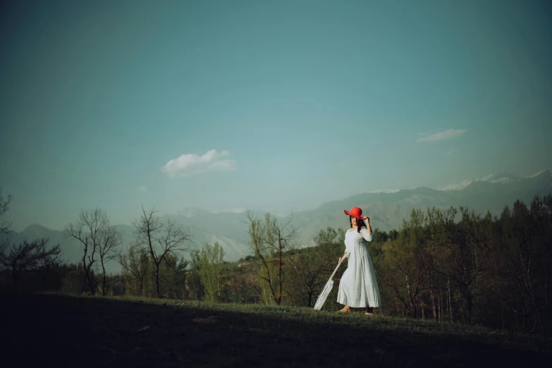 a woman in a white dress holding an orange hat